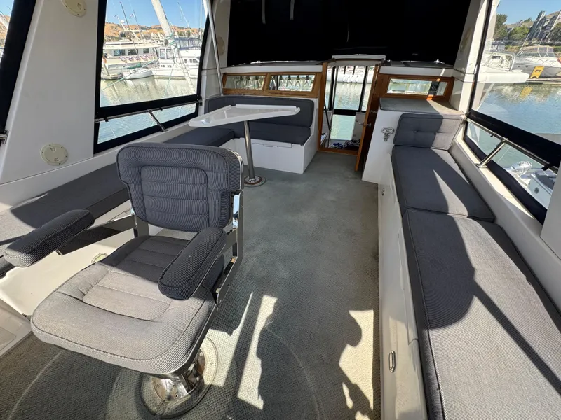 Slide: The Image of Interior of a 1990 Nova 48 yacht with gray seating and marina view. - 10
