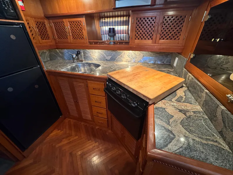 Slide: The Image of Compact kitchen in a 1990 Nova 48 boat with wood cabinets and granite countertops. - 36