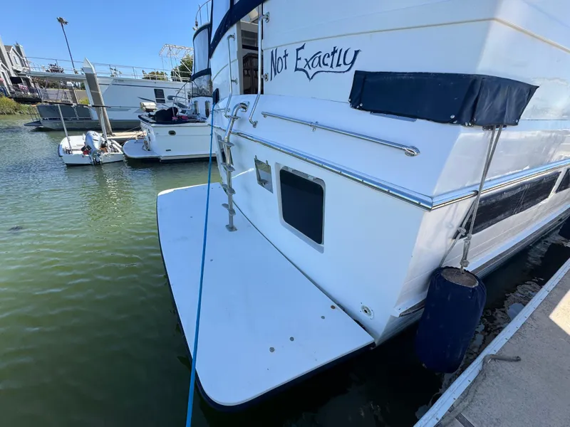 Slide: The Image of 1990 Nova 48 yacht docked, featuring "Not Exactly" name on the stern, calm marina setting. - 41