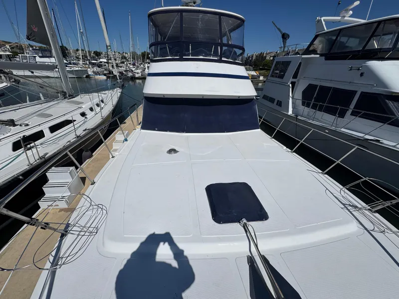 Slide: The Image of 1990 Nova 48 yacht docked at marina, surrounded by other boats under clear blue sky. - 5