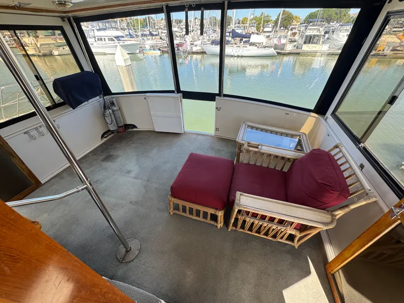 Slide: The Image of Interior of a 1990 Nova 48 yacht with red cushioned seating and marina view. - 8