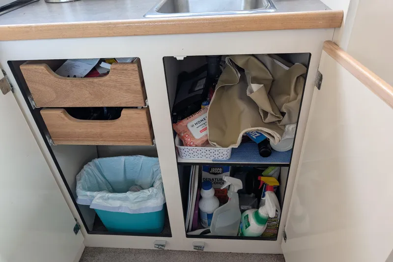 Slide: The Image of Under-sink storage in 1997 Bayliner 2859 Ciera Express, featuring cleaning supplies and trash bin. - 33