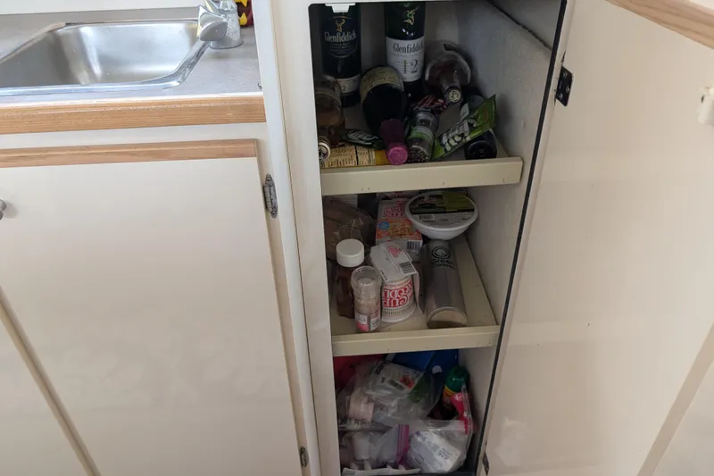 Slide: The Image of Cupboard with assorted items inside a 1997 Bayliner 2859 Ciera Express boat kitchen. - 34