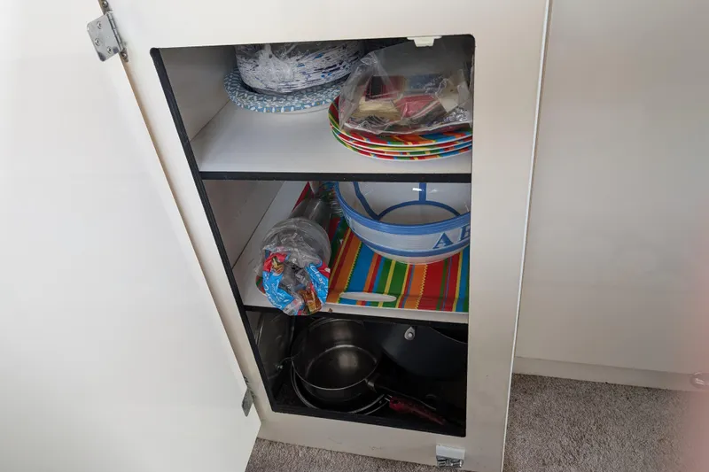 Slide: The Image of Open cabinet with colorful dishes and cookware on a Bayliner 2859 Ciera Express, 1997 model. - 35