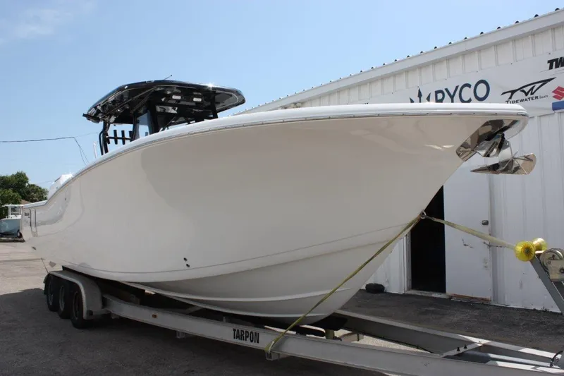 Slide: The Image of 2025 Tidewater 320 CC Adventure boat on trailer, parked outside a building. - 13