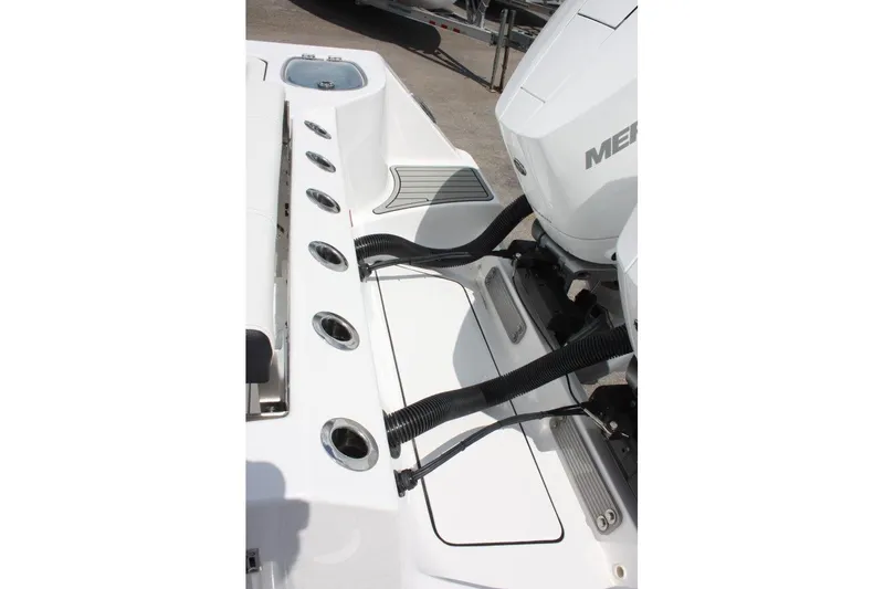 Slide: The Image of 2025 Tidewater 320 CC Adventure boat engine area with rod holders and Mercury outboard. - 16