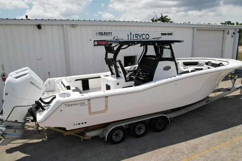 Slide: The Image of 2025 Tidewater 320 CC Adventure boat on trailer, parked outside a warehouse. - 3