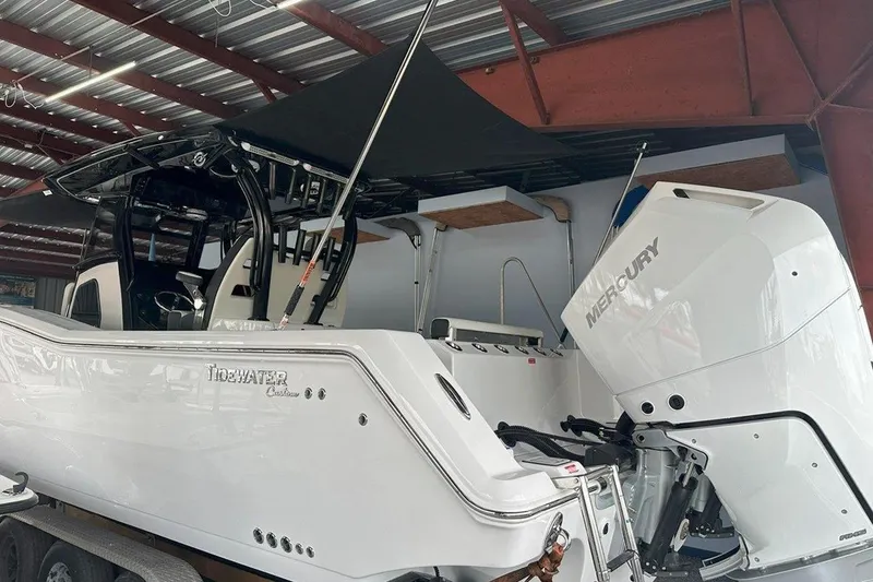 Slide: The Image of 2025 Tidewater 320 CC Adventure boat with Mercury engine in a covered storage area. - 46
