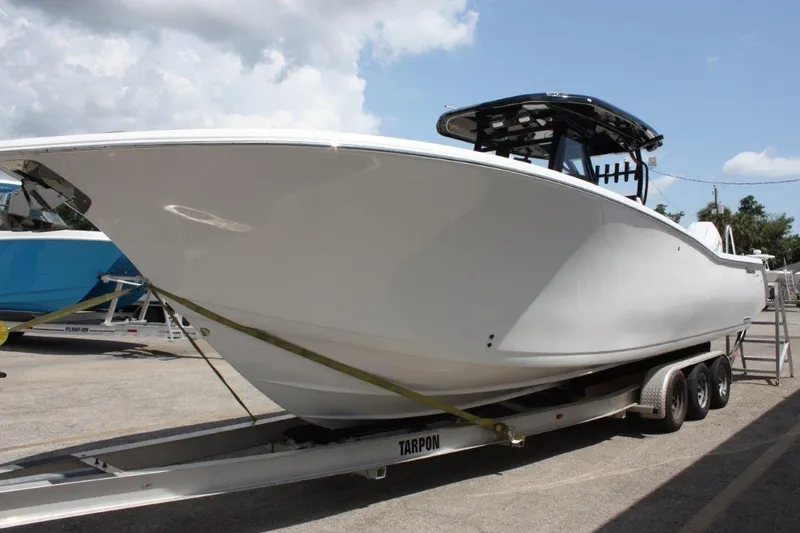 Slide: The Image of 2025 Tidewater 320 CC Adventure boat on trailer under cloudy sky. - 9