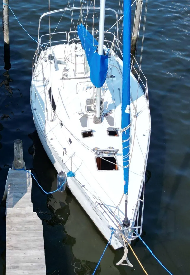 Slide: The Image of 1987 Hunter 34 sailboat docked, featuring white hull and blue sail cover. - 12