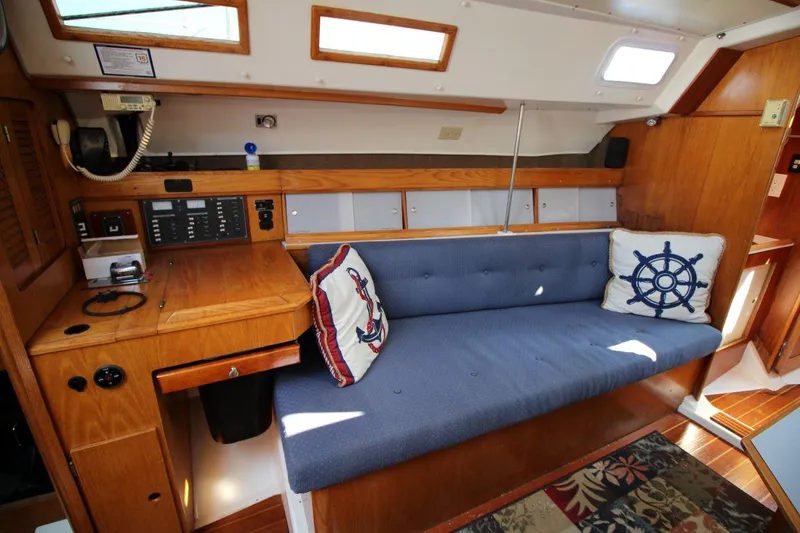 Slide: The Image of Interior of 1987 Hunter 34 sailboat with blue cushioned seating and nautical-themed pillows. - 15