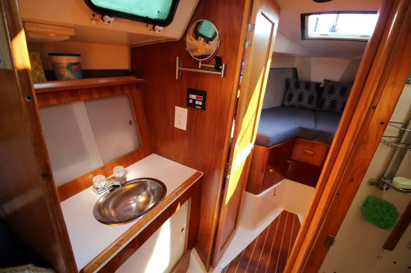 Slide: The Image of 1987 Hunter 34 yacht interior with sink, wooden cabinetry, and cozy sleeping area. - 19