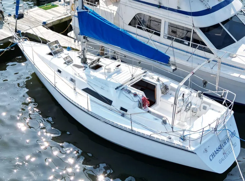 Slide: The Image of 1987 Hunter 34 sailboat docked, featuring a sleek white design and blue sail cover. - 9