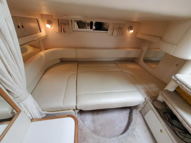 Slide: The Image of Interior of 2000 Sea Ray 310 Sundancer, featuring a cozy, cream-colored cabin with soft lighting. - 11