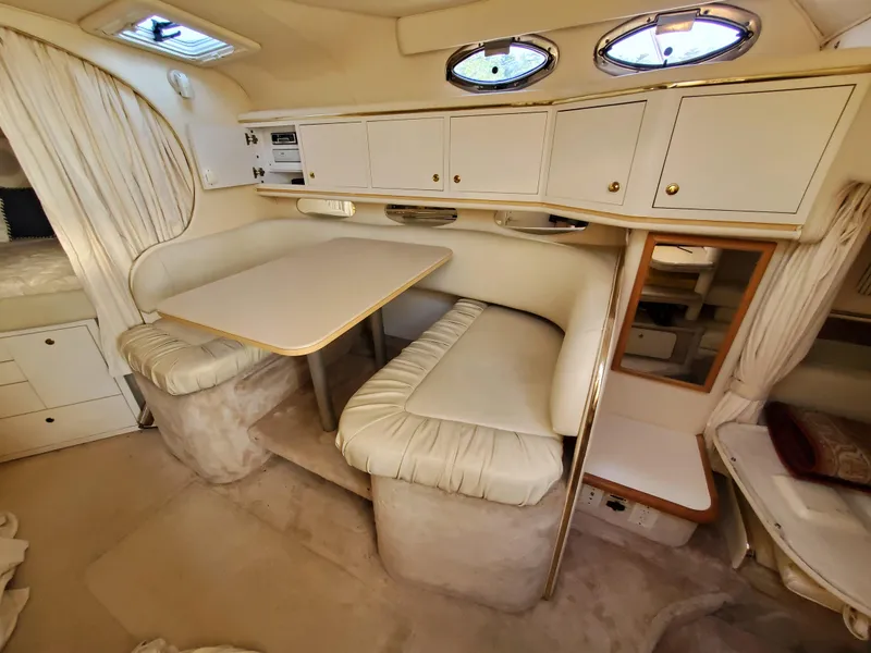 Slide: The Image of Interior of 2000 Sea Ray 310 Sundancer with cozy dining area and storage cabinets. - 12