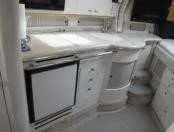 Slide: The Image of 2000 Sea Ray 310 Sundancer yacht interior kitchen with white cabinetry and appliances. - 15