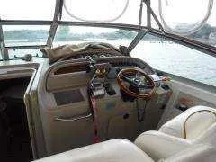 Slide: The Image of 2000 Sea Ray 310 Sundancer helm with steering wheel and controls, overlooking water. - 6