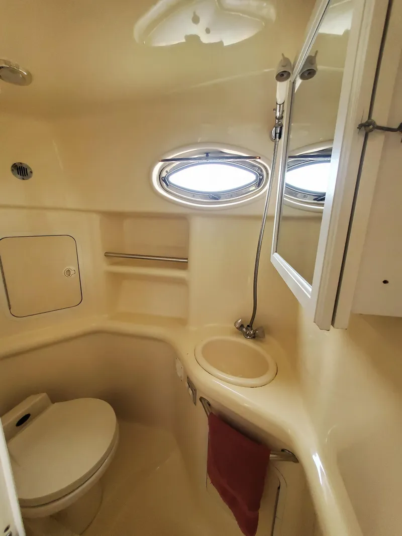 Slide: The Image of 2000 Sea Ray 310 Sundancer bathroom with toilet, sink, and oval window. - 9