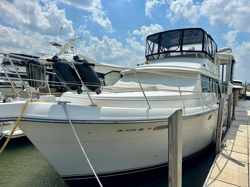 The Image of 1995 Carver 440 Aft Cabin Motor Yacht docked under a partly cloudy sky. - 0
