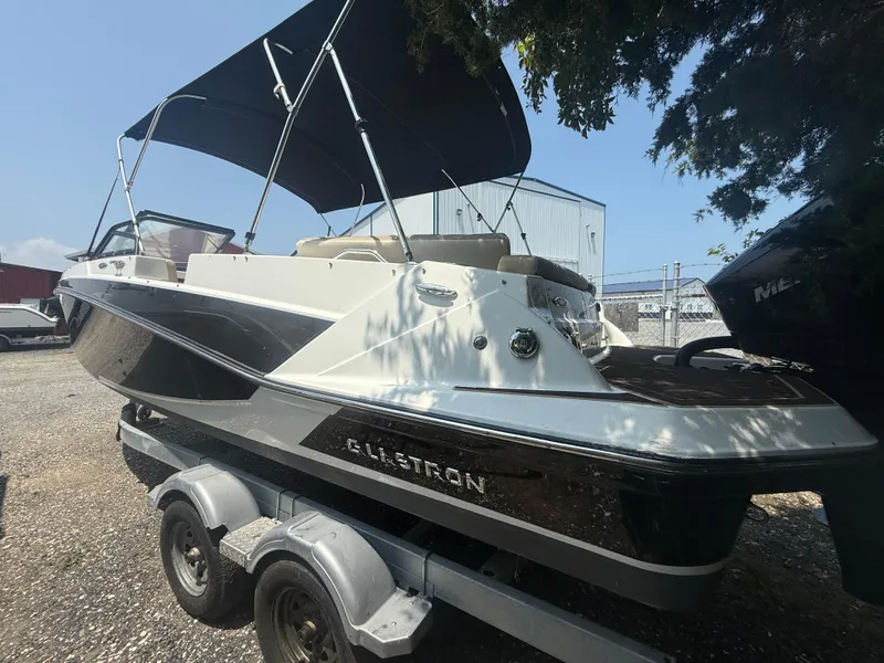 Slide: The Image of 2022 Glastron GTD 220 boat on trailer with canopy, parked outdoors. - 4