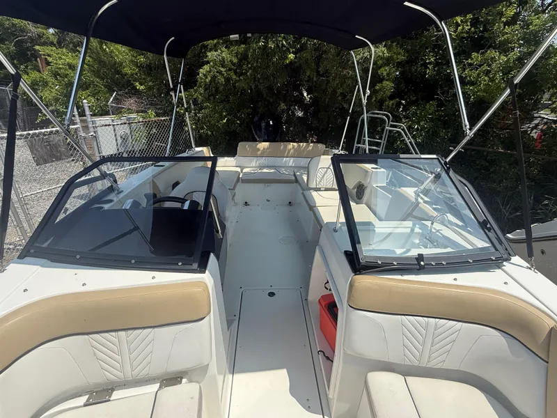 Slide: The Image of 2022 Glastron GTD 220 boat interior with seating and windshield, docked outdoors. - 7