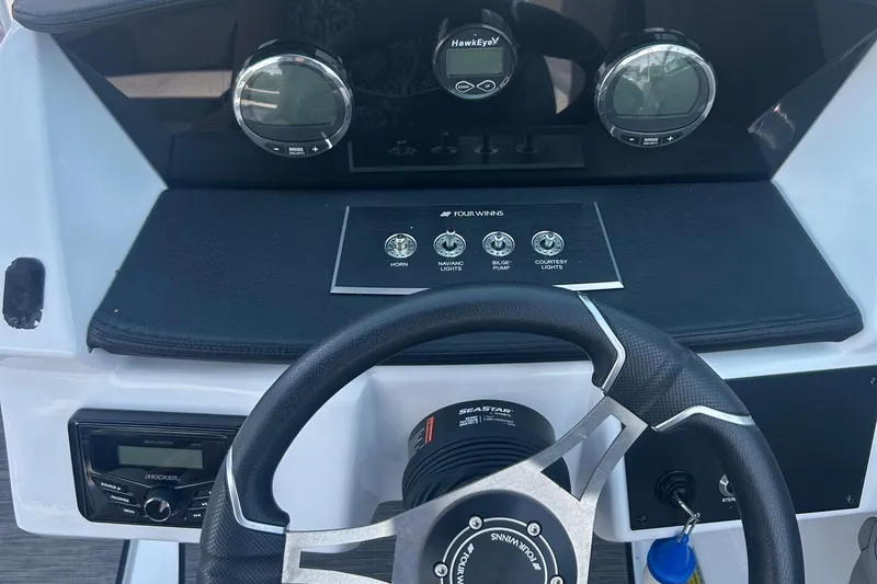 Slide: The Image of 2023 Four Winns H1 OB boat dashboard with steering wheel and control panel. - 14