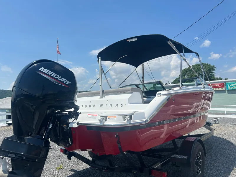Slide: The Image of 2023 Four Winns H1 OB boat with Mercury outboard engine, red and white design, on trailer. - 4