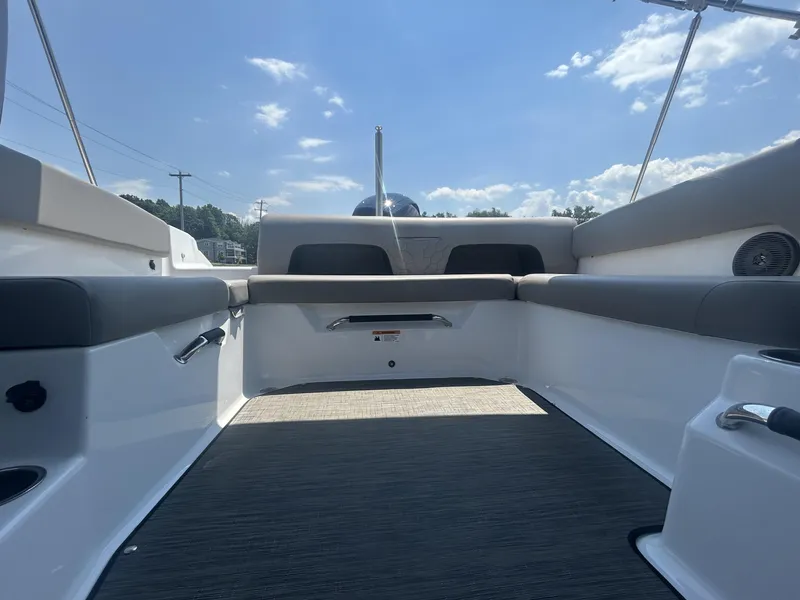 Slide: The Image of 2023 Four Winns H1 OB boat interior with cushioned seating and open deck under blue sky. - 7