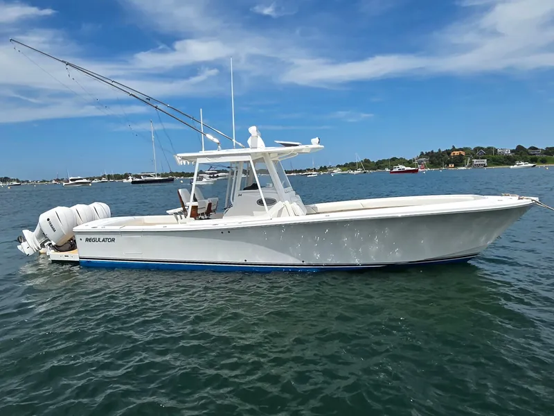 The Image of 2020 Regulator 34 Center Console boat on calm water near coastal homes. - 0