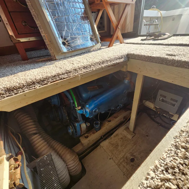 Slide: The Image of Engine compartment of a 1989 Trojan F36 boat, featuring a blue engine and carpeted flooring. - 16