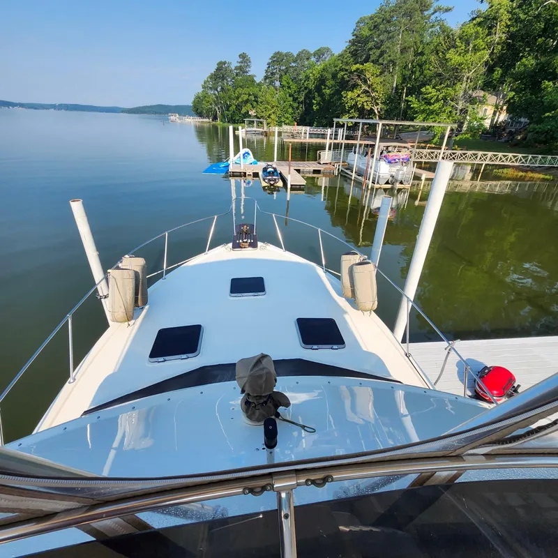 Slide: The Image of 1989 Trojan F36 yacht docked on a serene lake with lush greenery. - 20