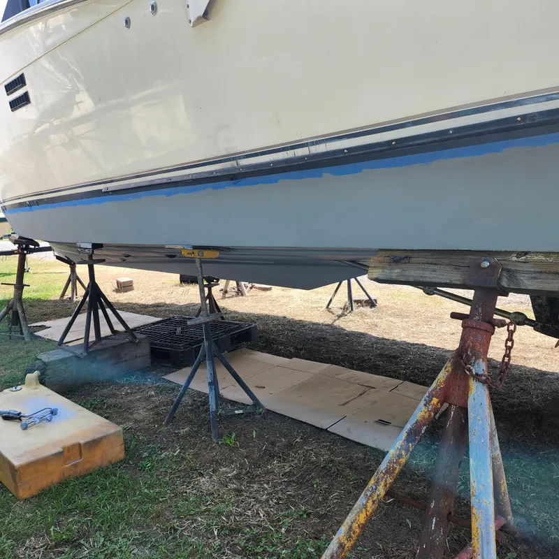 Slide: The Image of 1989 Trojan F36 boat on stands for maintenance, hull partially painted. - 22