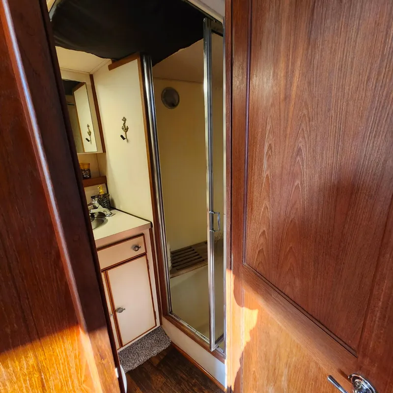 Slide: The Image of Interior of 1989 Trojan F36 boat featuring wooden cabinetry and compact bathroom. - 9