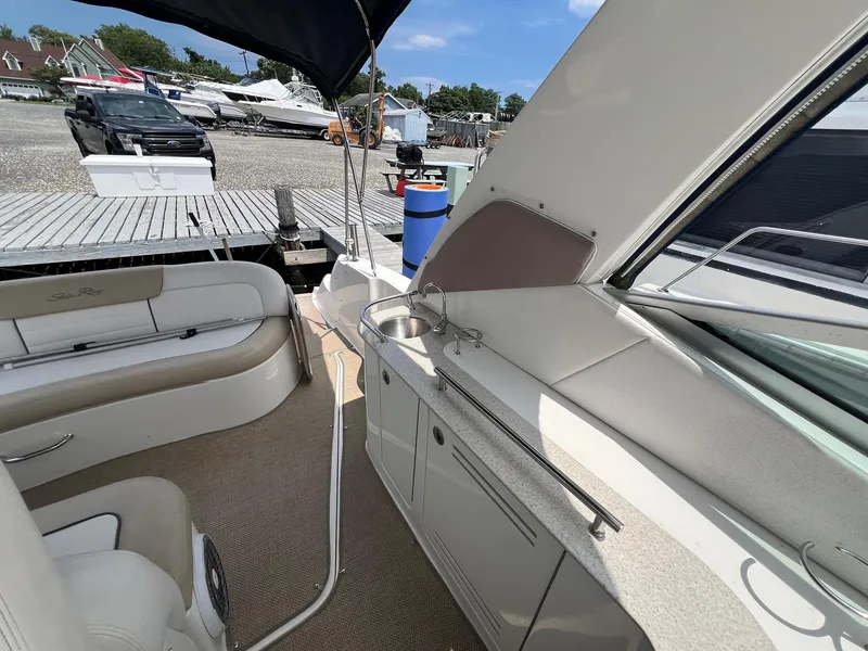 Slide: The Image of 2010 Sea Ray 330 Sundancer interior with seating and kitchenette, docked at marina. - 10