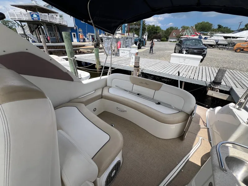 Slide: The Image of 2010 Sea Ray 330 Sundancer boat interior with beige seating at a marina dock. - 11