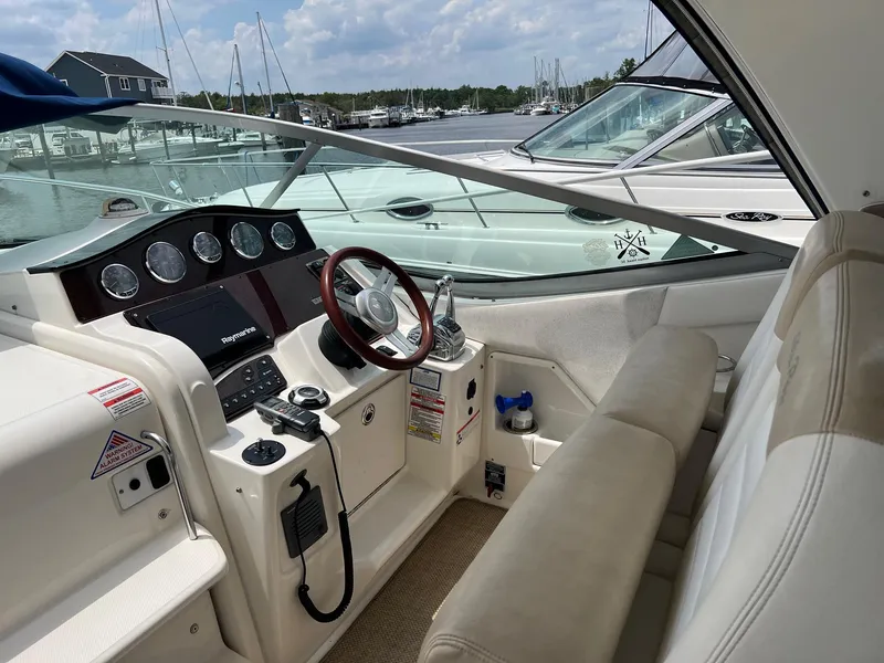 Slide: The Image of 2010 Sea Ray 330 Sundancer cockpit with steering wheel and control panel, docked at marina. - 13