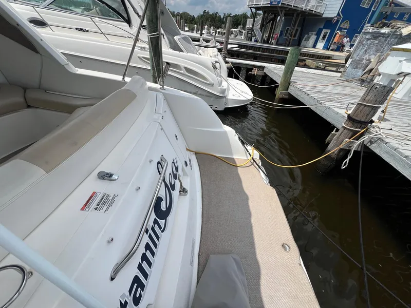 Slide: The Image of 2010 Sea Ray 330 Sundancer docked at marina, featuring spacious deck and seating area. - 6