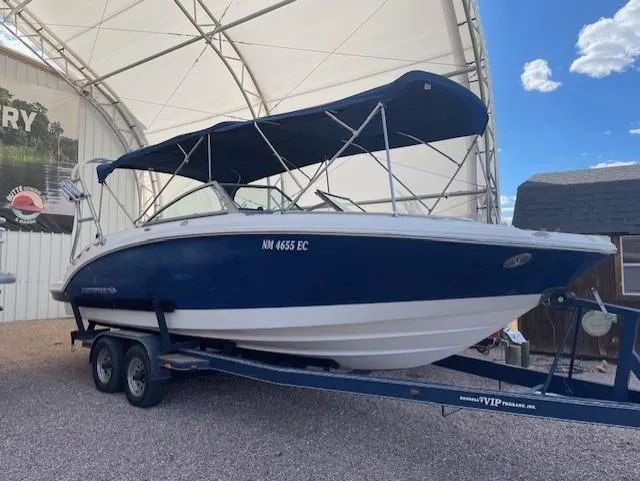 The Image of 2008 Chaparral Sunesta 264 boat on trailer under canopy, blue and white design. - 1
