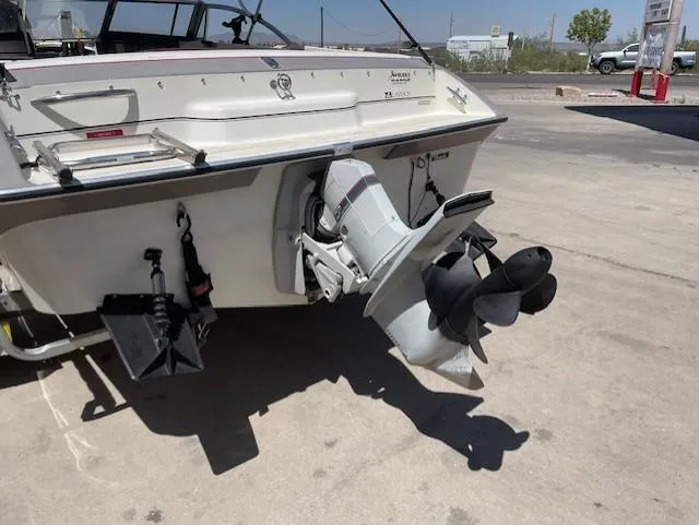 Slide: The Image of 1990 Larson 190 I/O boat stern with outboard motor and propeller in a parking area. - 2