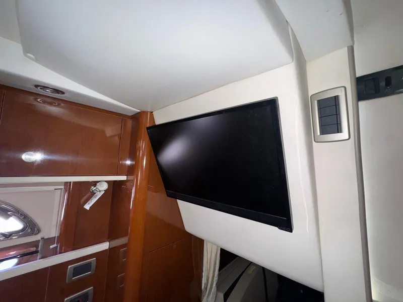 Slide: The Image of Interior of 2014 Sea Ray 330 Sundancer with mounted flat-screen TV and wooden cabinetry. - 20