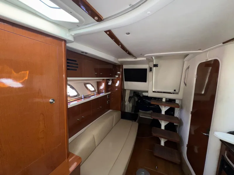 Slide: The Image of 2014 Sea Ray 330 Sundancer interior with wood finish, beige seating, and modern amenities. - 24