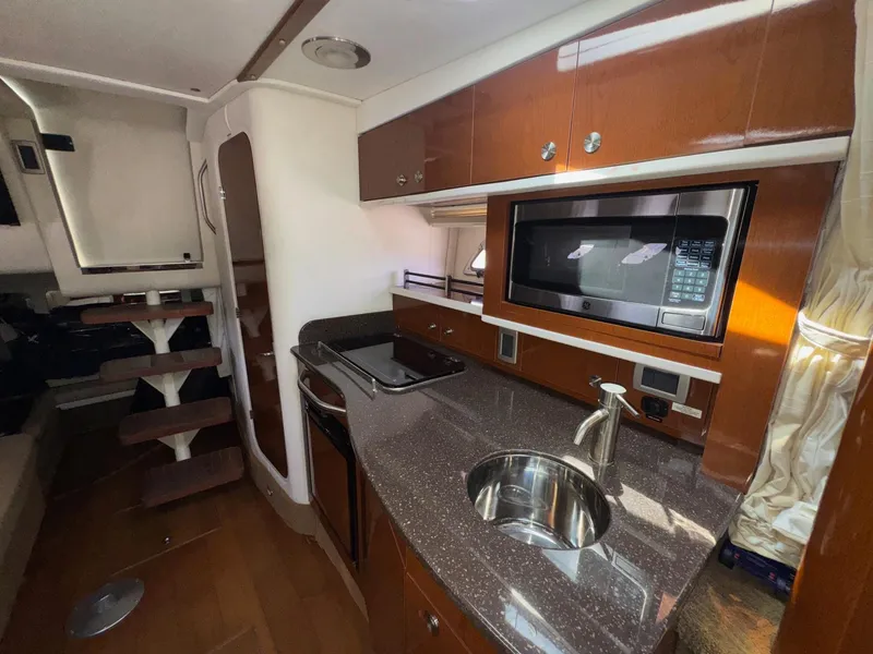 Slide: The Image of 2014 Sea Ray 330 Sundancer interior with kitchenette, microwave, and wooden cabinetry. - 25