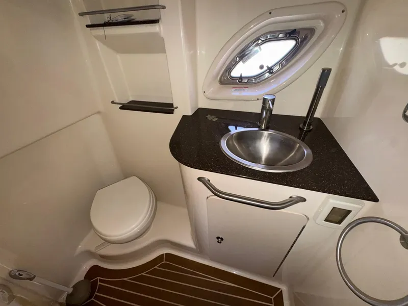 Slide: The Image of 2014 Sea Ray 330 Sundancer bathroom with sink, toilet, and porthole window. - 26