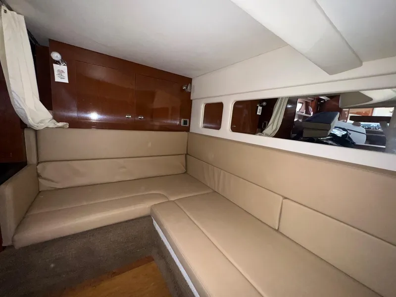 Slide: The Image of Interior of 2014 Sea Ray 330 Sundancer with beige seating and wooden cabinetry. - 30