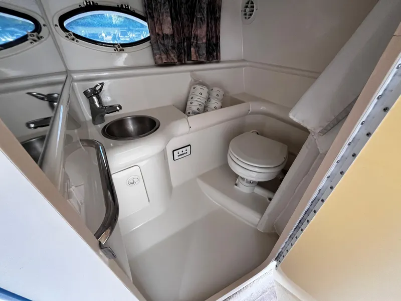 Slide: The Image of 1999 Formula 33 SS boat bathroom with sink, toilet, and porthole windows. - 22