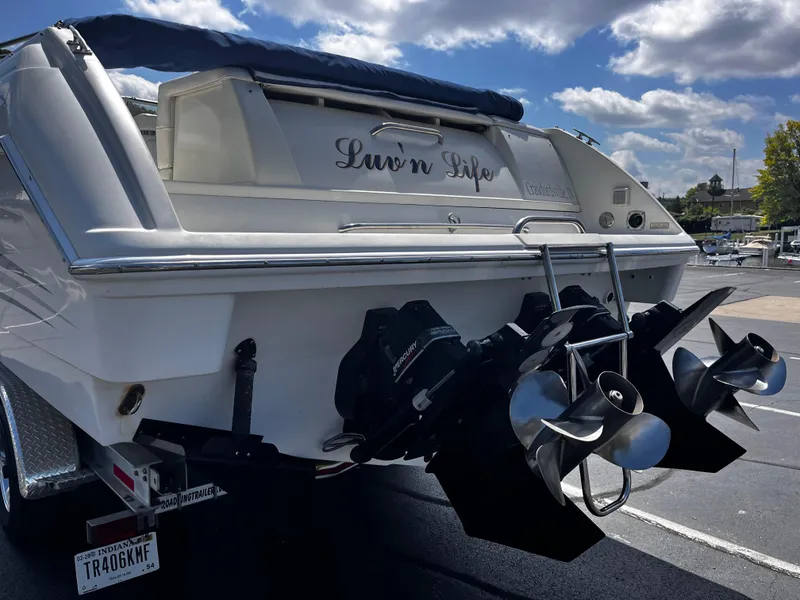 Slide: The Image of 1999 Formula 33 SS boat with dual propellers, parked on a trailer under a cloudy sky. - 4