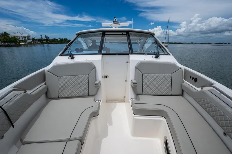 Slide: The Image of 2023 Pursuit DC 365 Dual Console boat interior with gray seating, on calm water. - 11