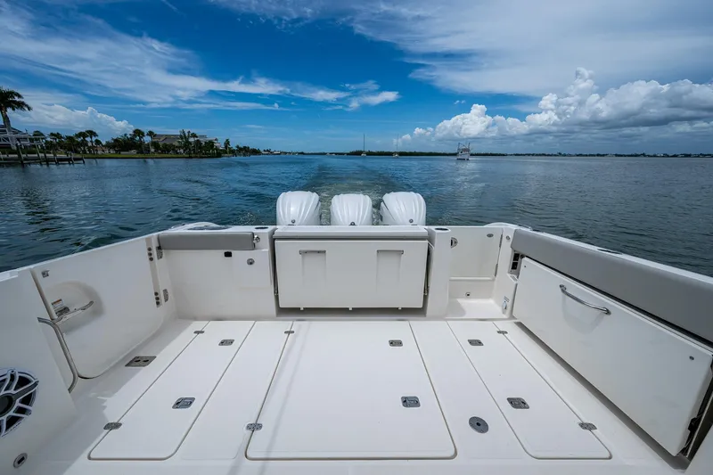 Slide: The Image of 2023 Pursuit DC 365 Dual Console boat on calm water, showcasing spacious deck and triple engines. - 18