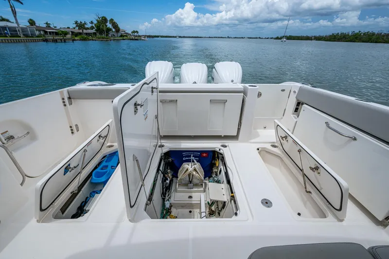 Slide: The Image of 2023 Pursuit DC 365 Dual Console boat with open storage compartments on a calm waterway. - 22