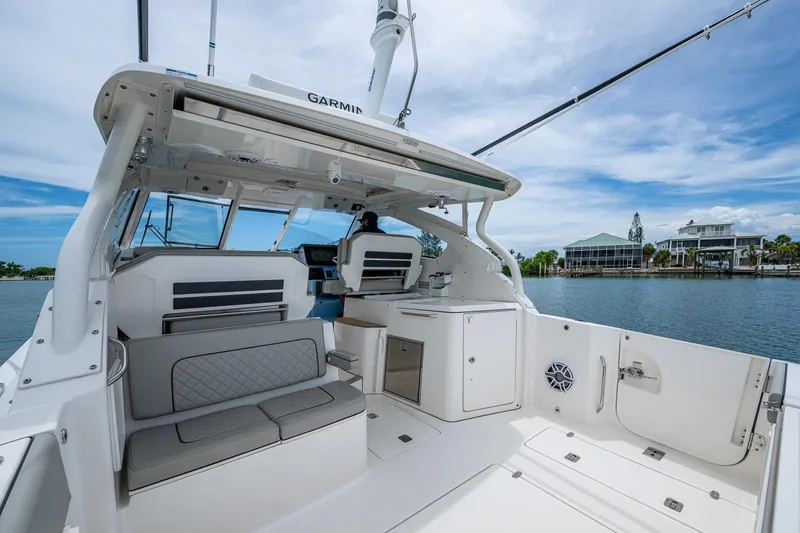 Slide: The Image of 2023 Pursuit DC 365 Dual Console boat interior with seating and helm, docked by waterfront homes. - 27